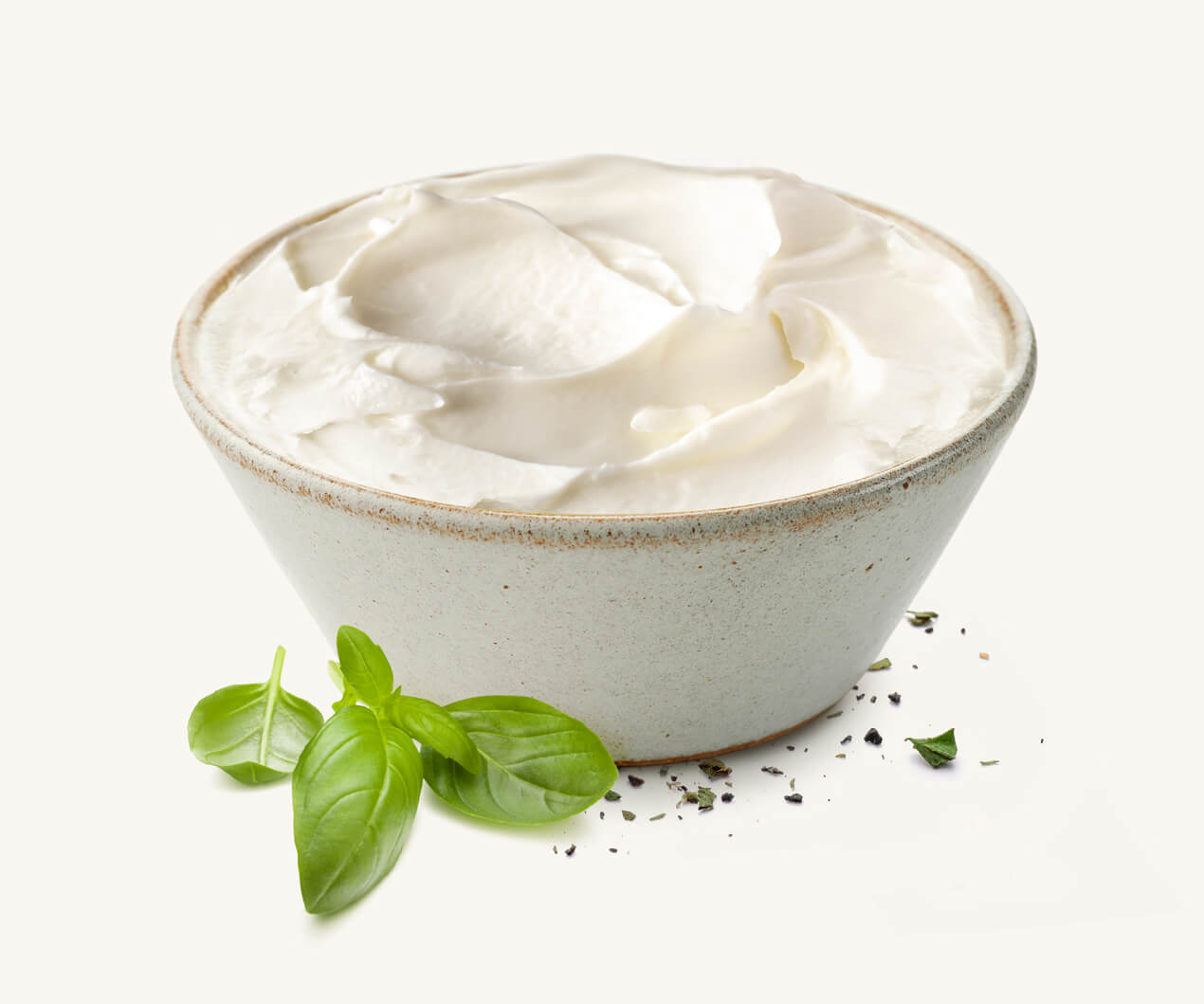 Pote de queso crema acompañado de hojitas de albahaca y orégano seco